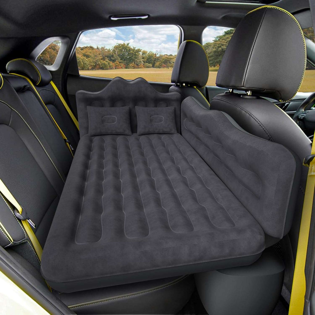 Inflatable mattress set up in the back of a car with yellow accents.