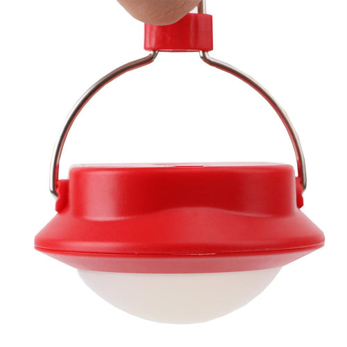 Red camping lantern held by a hand on a white background