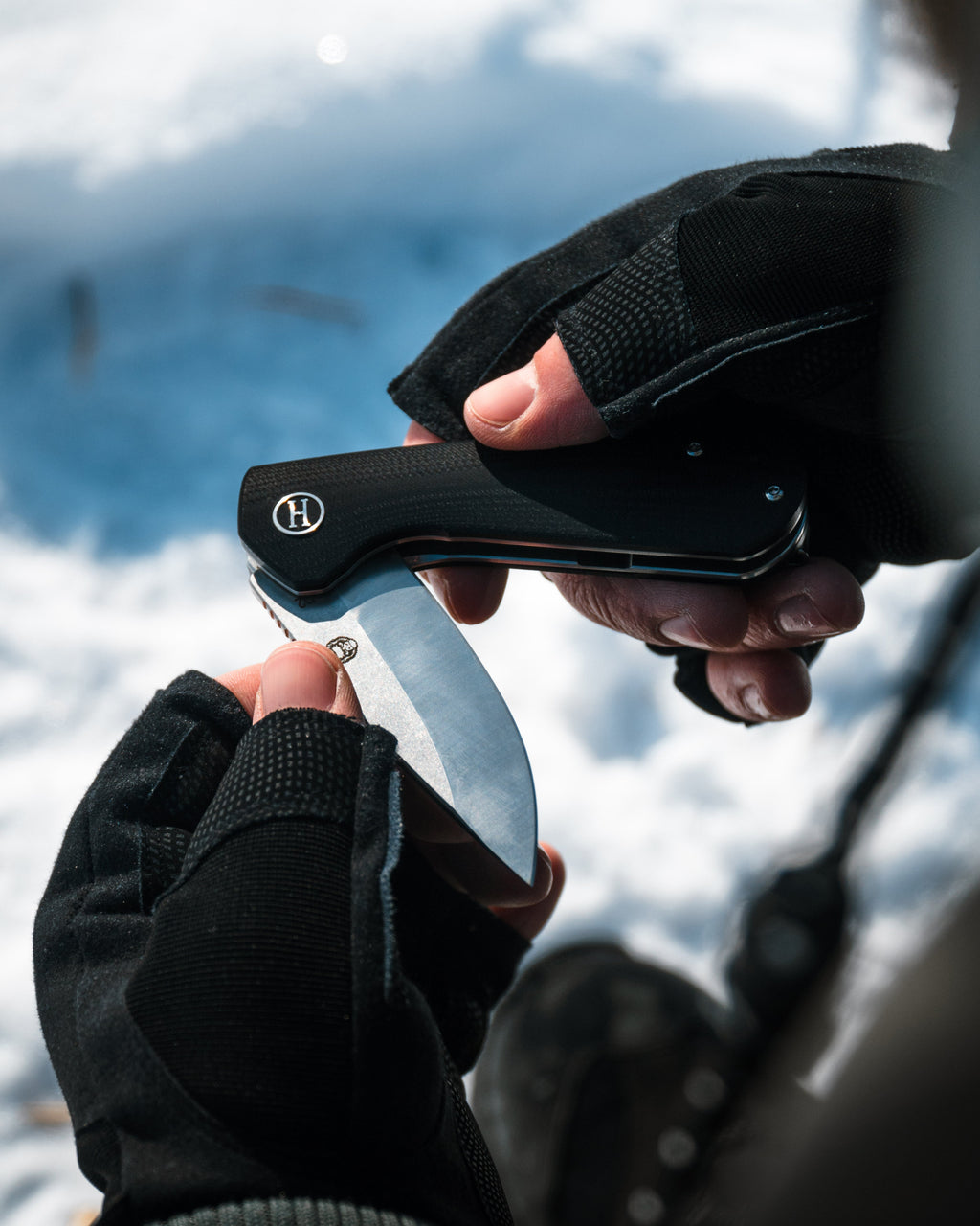 Person using a black and silver tool with a blurred snowy background