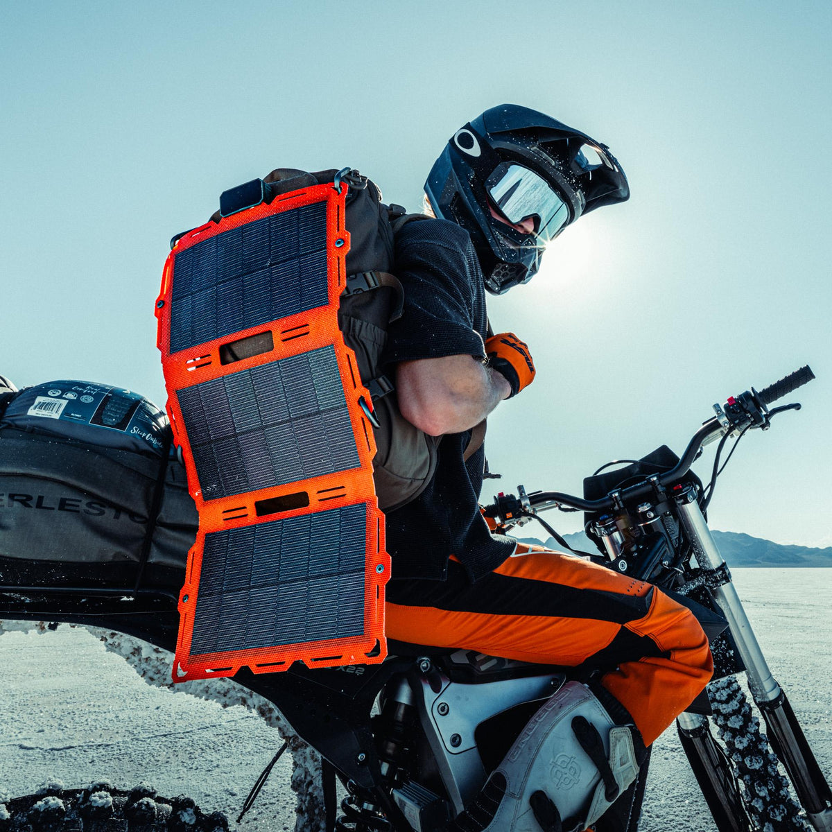 Person on a motorcycle with a large orange solar panel attached