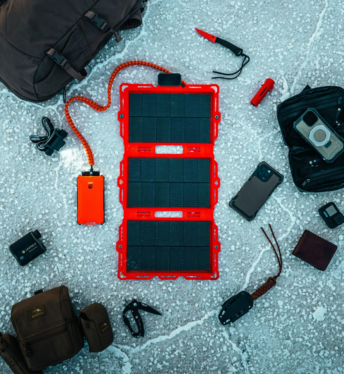 Red portable solar panel with camping gear on a textured surface