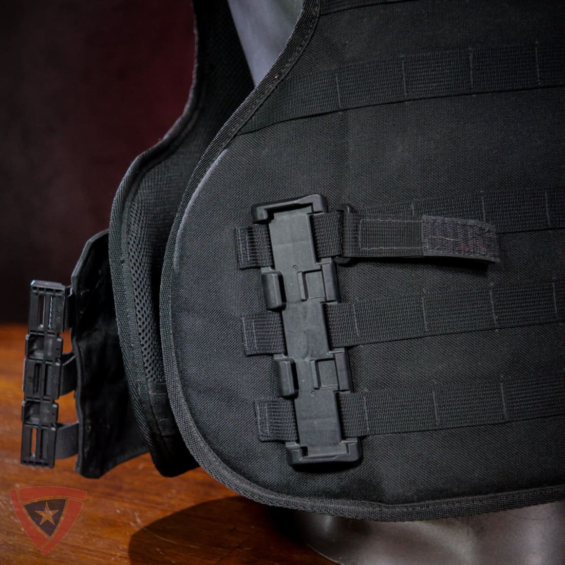 Black tactical vest with multiple straps on a wooden surface