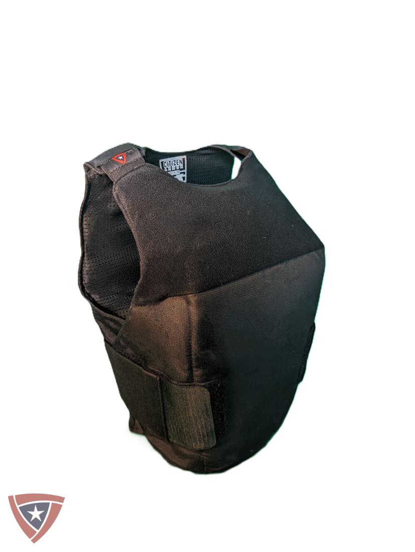 A black tactical plate carrier vest shown from a three-quarters angle on a plain white background, featuring a hook-and-loop strap closure at the bottom.