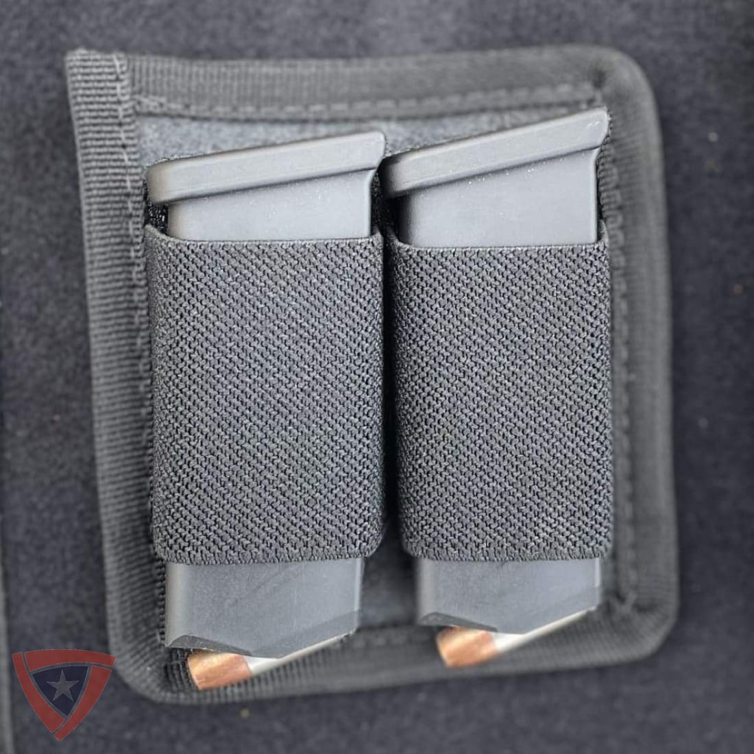 A dark gray dual magazine pouch with two gray polymer magazines inserted, shown in a close-up product shot against a dark gray background.