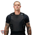 A man wearing a black protective vest over a black t-shirt, shown from the chest up against a plain white background.
