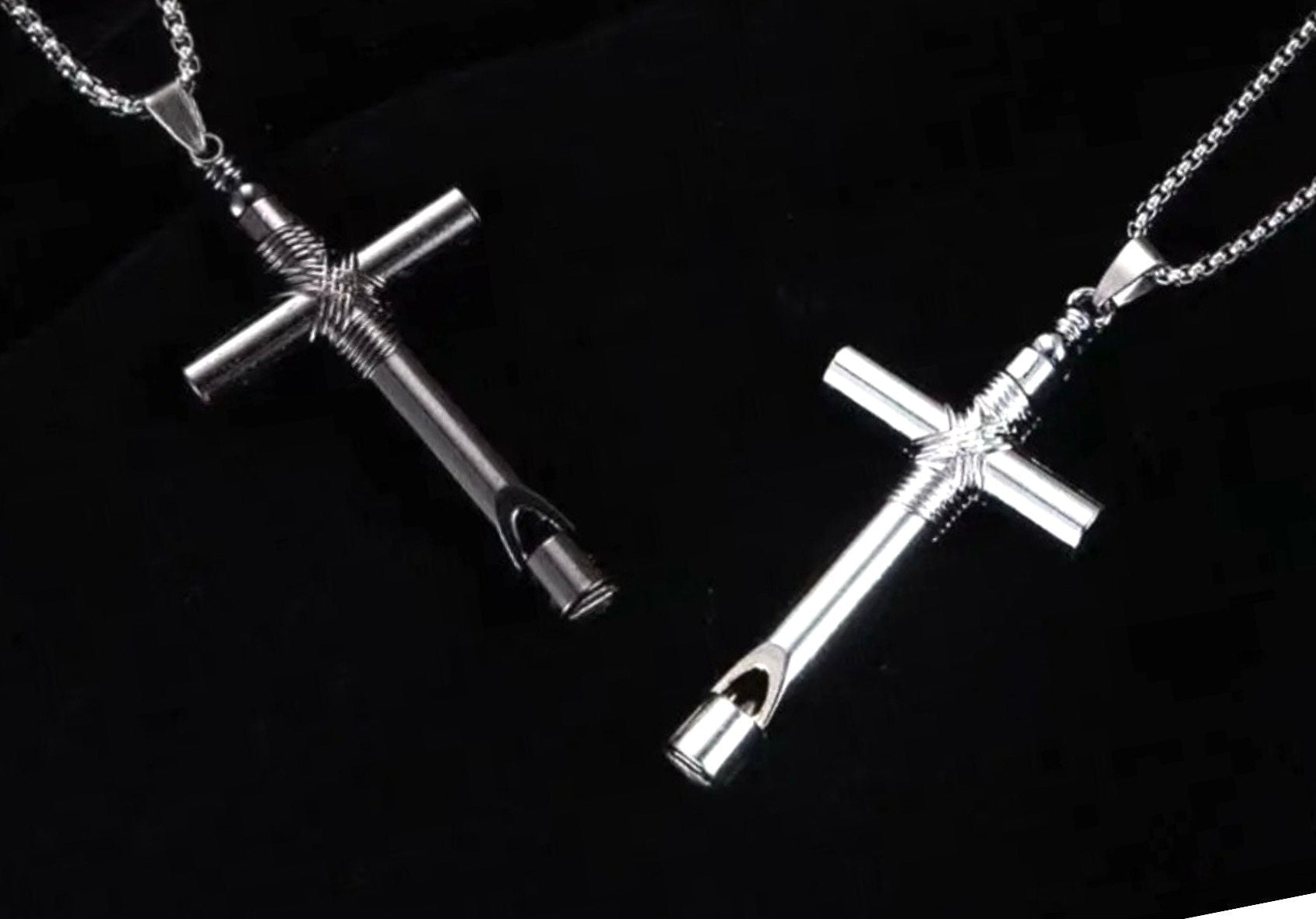 Two silver cross pendants on black background