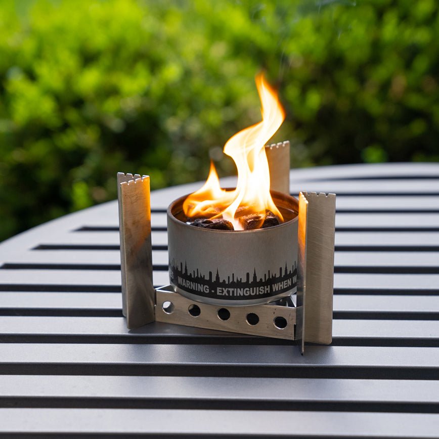 Portable fire pit with flames on a metal table outdoors